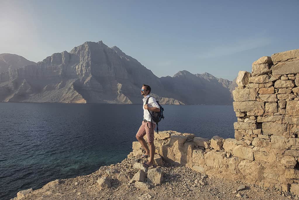 Ein Tourist steht am Strand von Musandam Oman und blickt auf das Meer