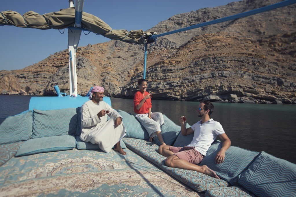 An Bord der traditionellen omanischen Dhau in Musandam, Oman - omanische Männer und Touristen